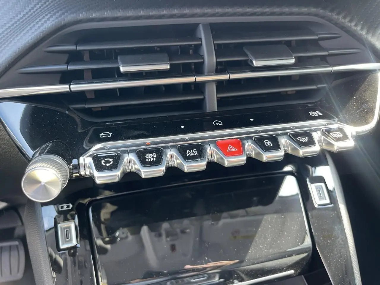 Vue rapprochée de la console centrale noire du Peugeot 208 2024 avec boutons chromés et écran tactile éteint.