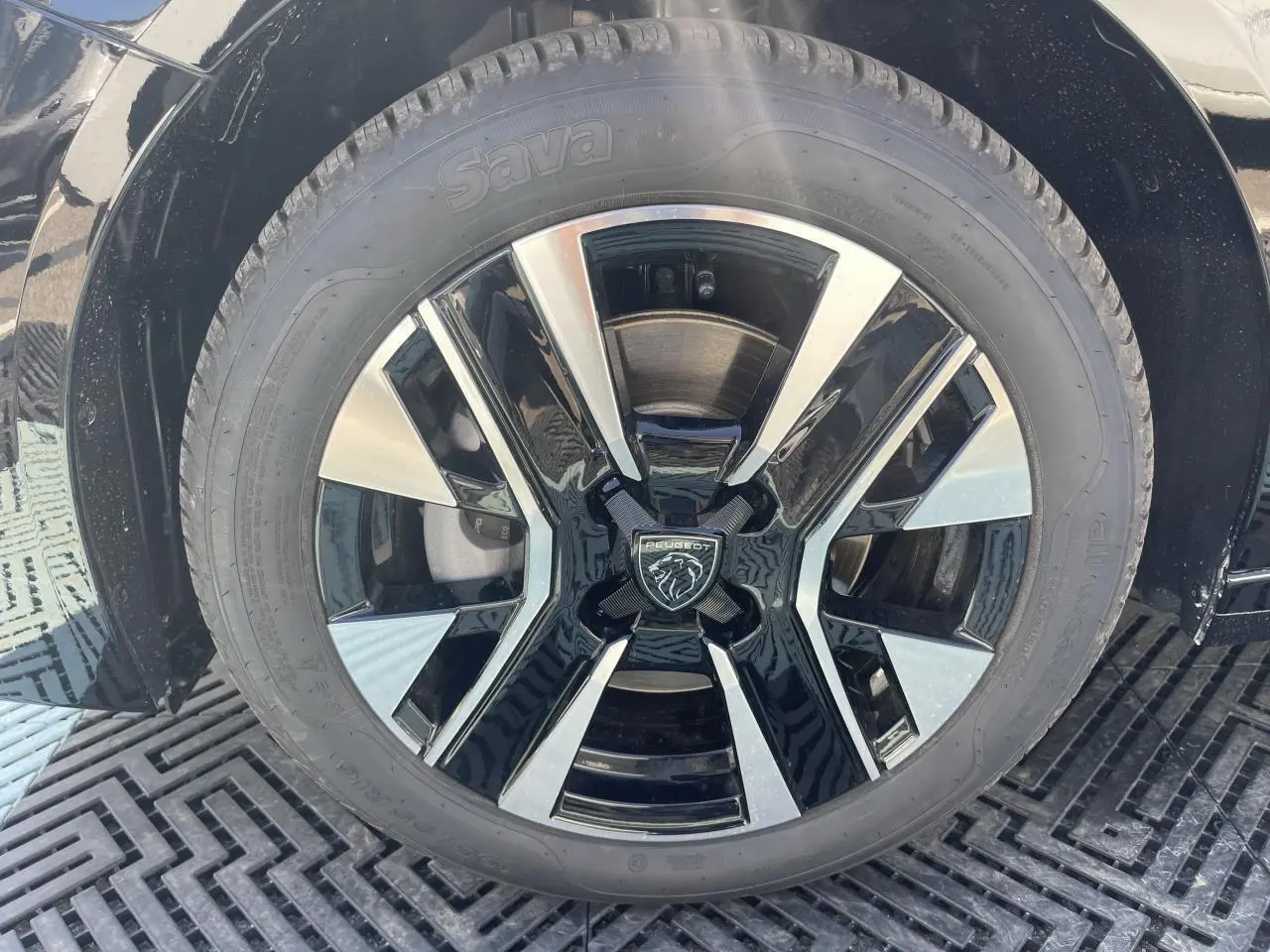 Gros plan sur la jante alliage 16'' NOMA diamantée biton noir et argent de la Peugeot 208 noir Onyx 2024.