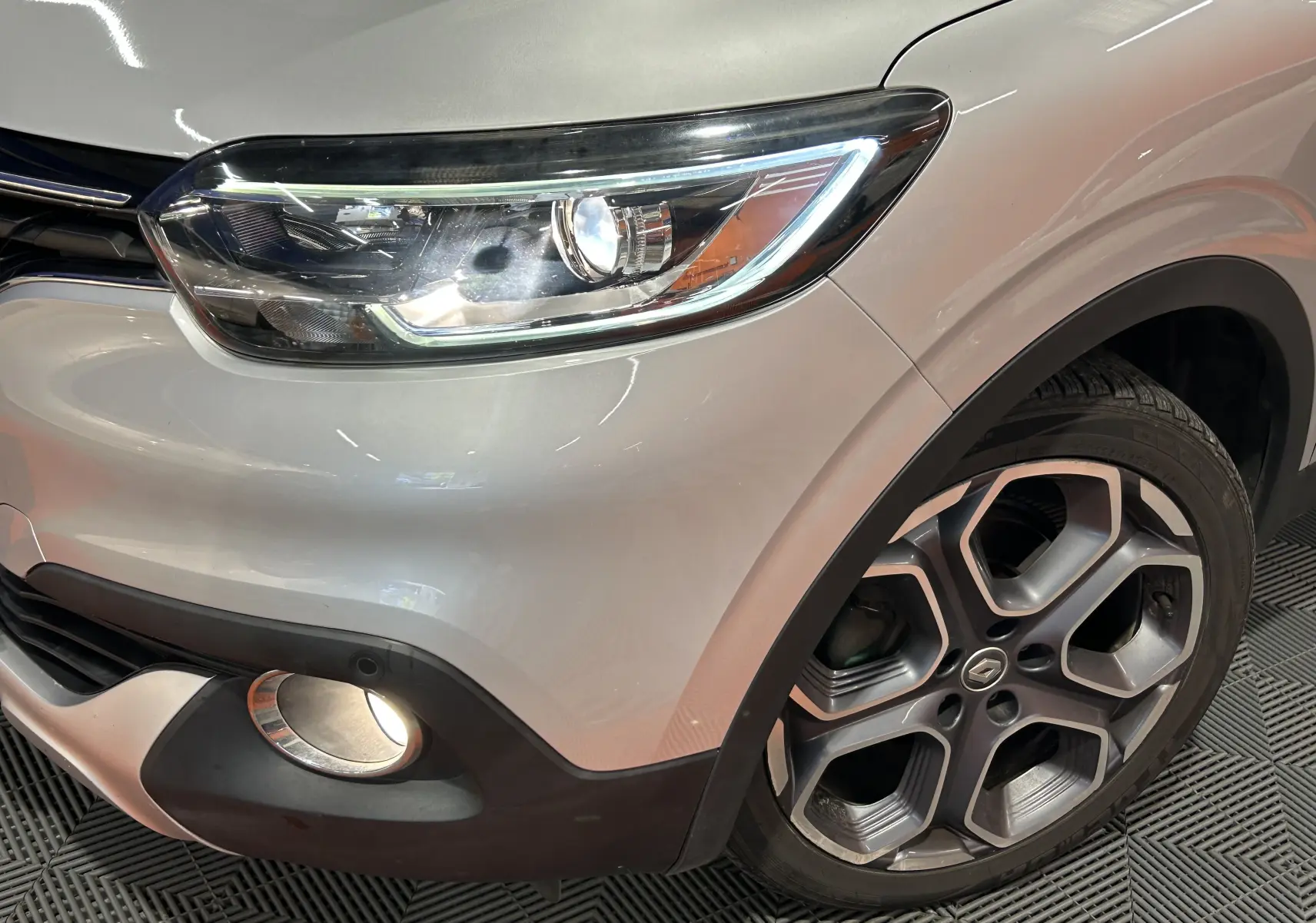 Gros plan sur l'avant droit gris du Renault Kadjar 2015, mettant en valeur le phare LED et la jante alliage distinctive.