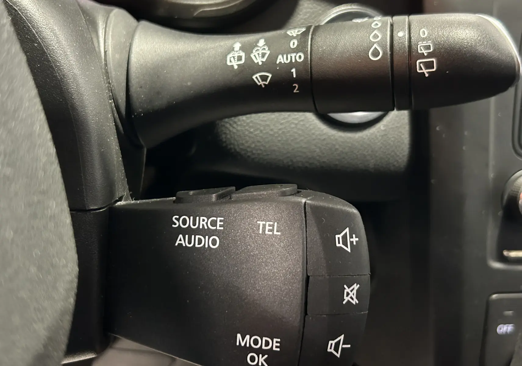 Gros plan sur les commandes audio et essuie-glace noires du tableau de bord du Renault Kadjar gris 2015.