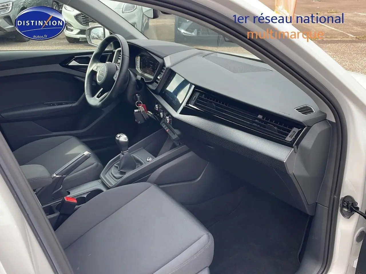 Intérieur avant droit d'une Audi A1 Sportback blanche 2022, volant cuir, boîte manuelle et tableau de bord moderne.