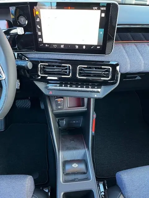Vue intérieure centrée sur la console centrale de la Renault R5 Techno 2024, avec écran tactile et zone de recharge par induction.