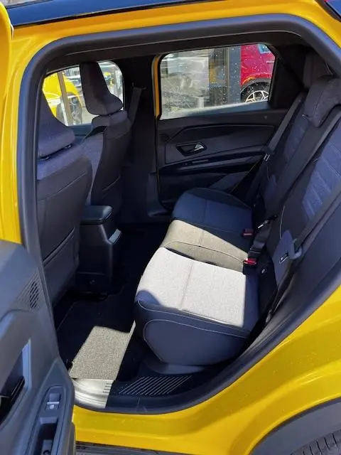 Vue intérieure arrière côté gauche d'une Renault R5 jaune 2024, montrant les sièges arrière en tissu gris et noir.