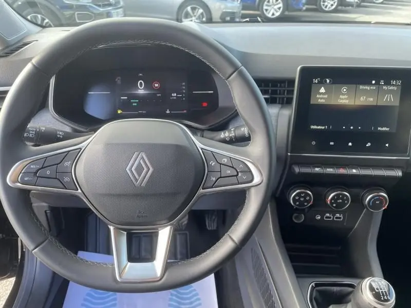 Vue intérieure centrée sur le volant noir de la Renault Clio V 1.5 DCI 100 Evolution 2025 avec tableau de bord numérique et écran tactile.