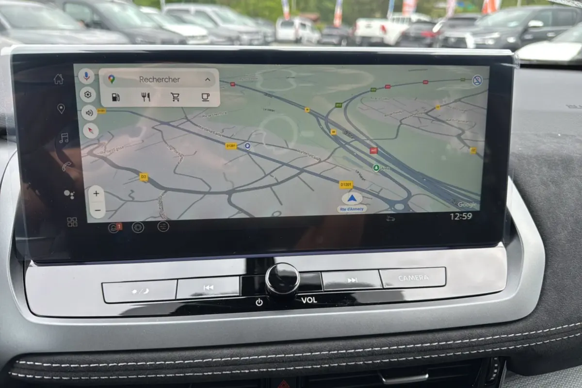 Écran tactile central du Nissan Qashqai E-POWER 205 Tekna Plus affichant une carte GPS, avec finition intérieure noire et surpiqûres blanches.