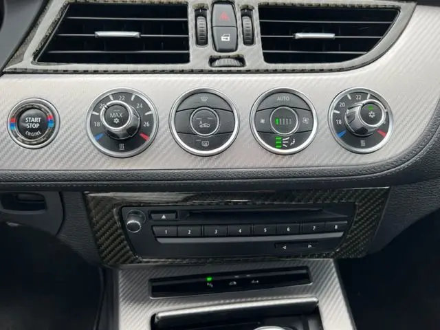 Tableau de bord du BMW Z4 Roadster 2012, détail des commandes climatisation et bouton Start/Stop sur finition M Sport grise.