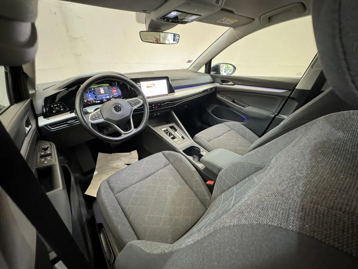 Vue intérieure avant droite de la Volkswagen Golf 2.0 TDI 2021, sièges gris et tableau de bord digital avec écran tactile.
