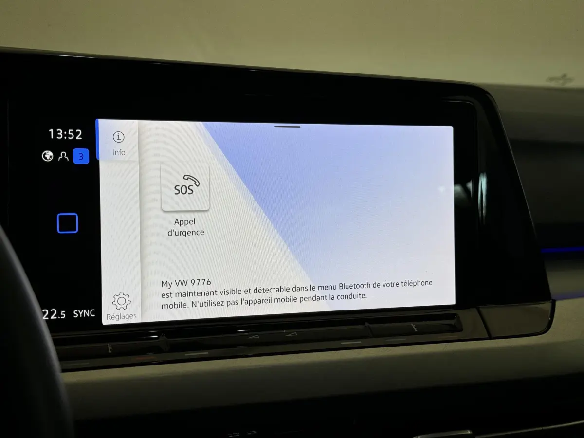 Écran tactile central affichant l'appel d'urgence dans l'habitacle d'une Volkswagen Golf bleu 2021.