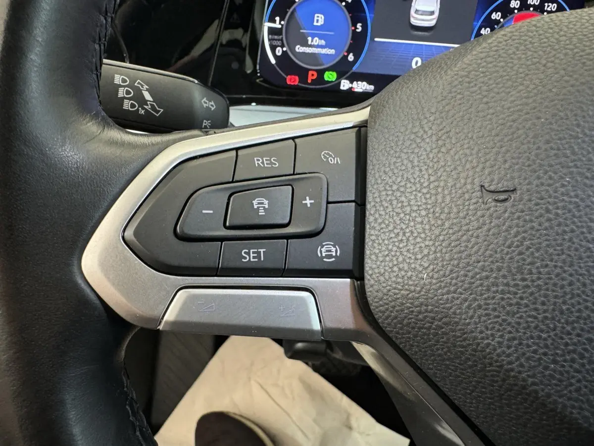 Gros plan sur les commandes au volant cuir noir d'une Volkswagen Golf 2.0 TDI 2021, avec tableau de bord numérique visible.