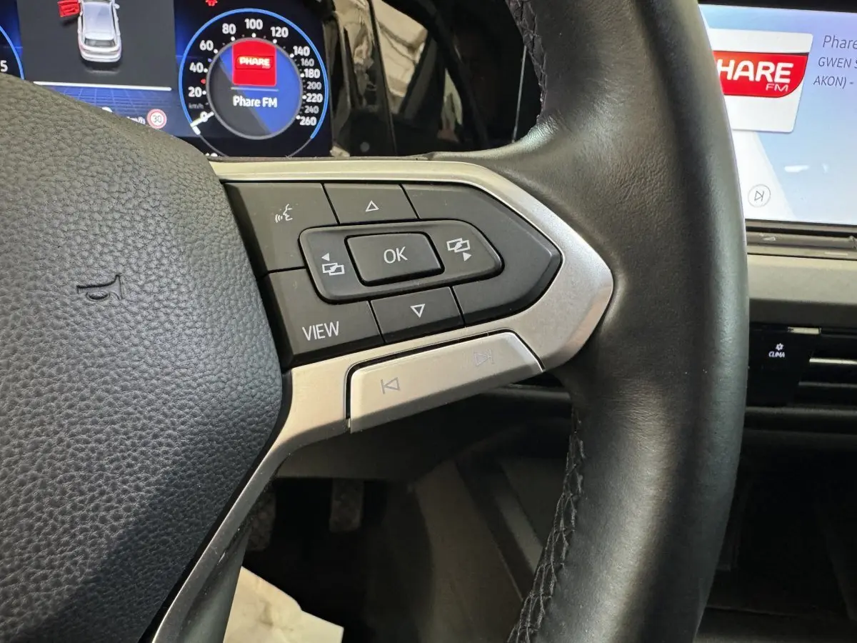 Gros plan sur le volant cuir noir de la Volkswagen Golf 2.0 TDI 2021 avec commandes multifonctions et tableau de bord digital.