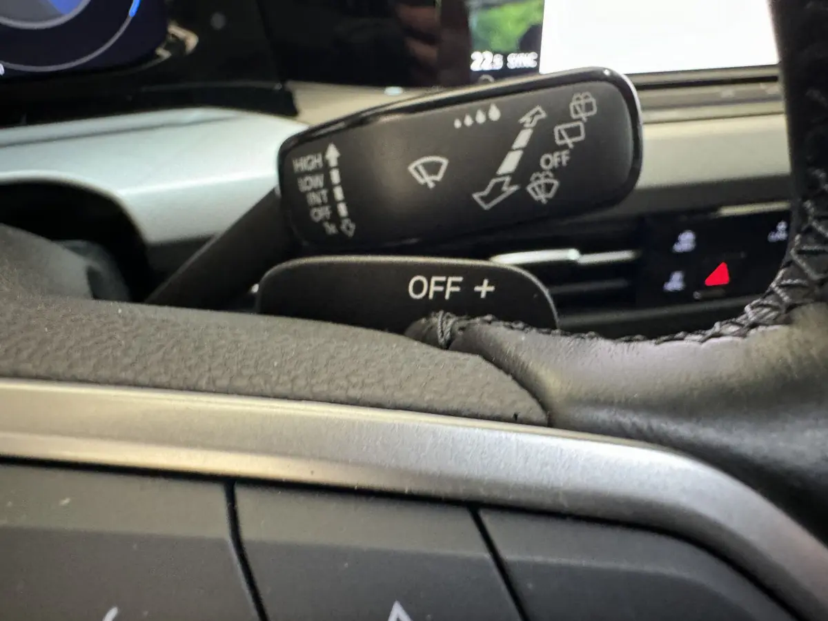 Gros plan sur la manette d'essuie-glace et le volant cuir de la Volkswagen Golf bleu, tableau de bord en arrière-plan flou.