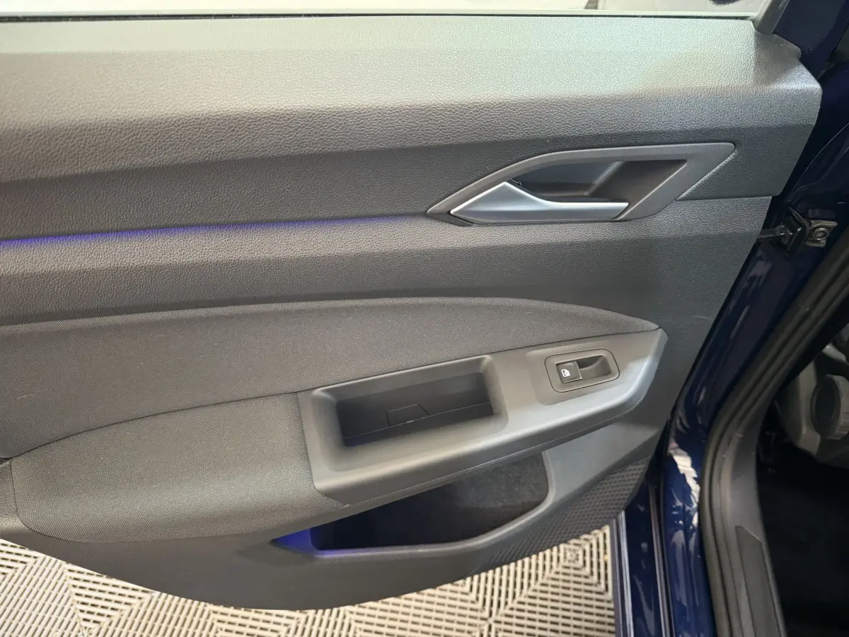 Intérieur côté gauche de la porte avant d'une Volkswagen Golf bleu 2021, avec bouton verrouillage et poignée grise.