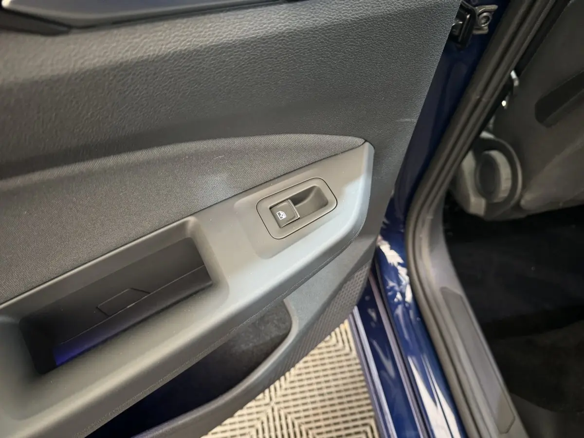 Gros plan sur la commande de lève-vitre de la porte avant gauche d'une Volkswagen Golf bleu 2021.