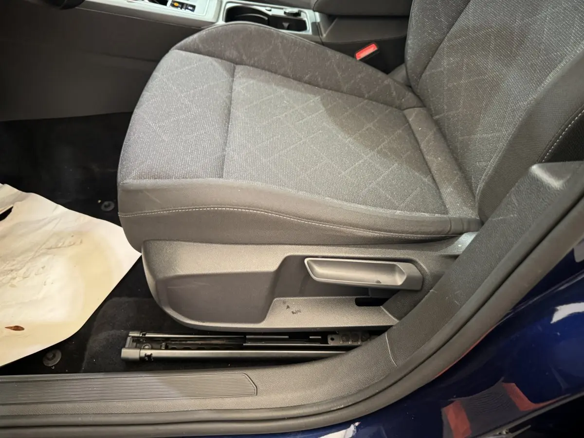 Gros plan sur le siège avant gauche tissu gris d'une Volkswagen Golf bleu 2021, avec réglage manuel visible.