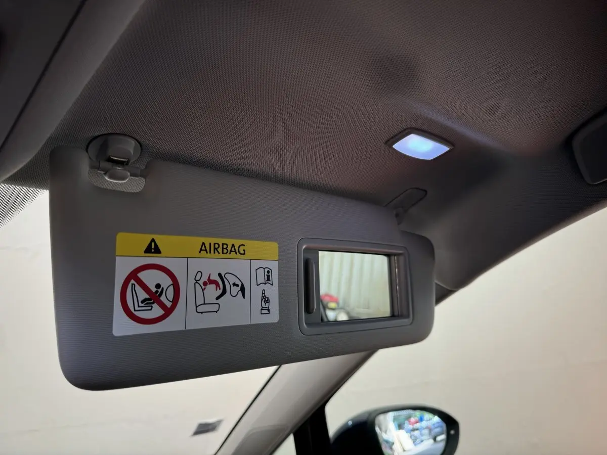 Détail du pare-soleil côté conducteur avec miroir et avertissement airbag dans une Volkswagen Golf bleu 2021.