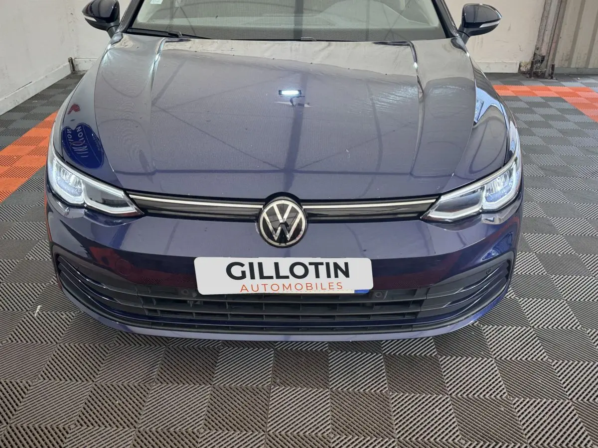 Vue avant rapprochée d'une Volkswagen Golf bleu foncé avec calandre noire et logo VW centré.