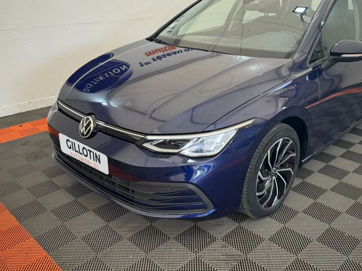 Vue 3/4 avant droit d'une Volkswagen Golf bleu profond avec phares LED et jantes alliage distinctives.