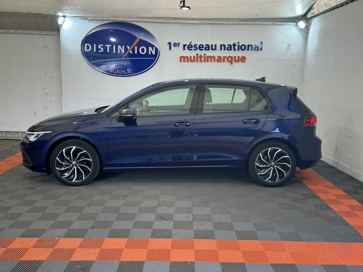 Profil côté gauche d'une Volkswagen Golf bleu foncé 2021, avec jantes alliage au design moderne, en intérieur showroom.