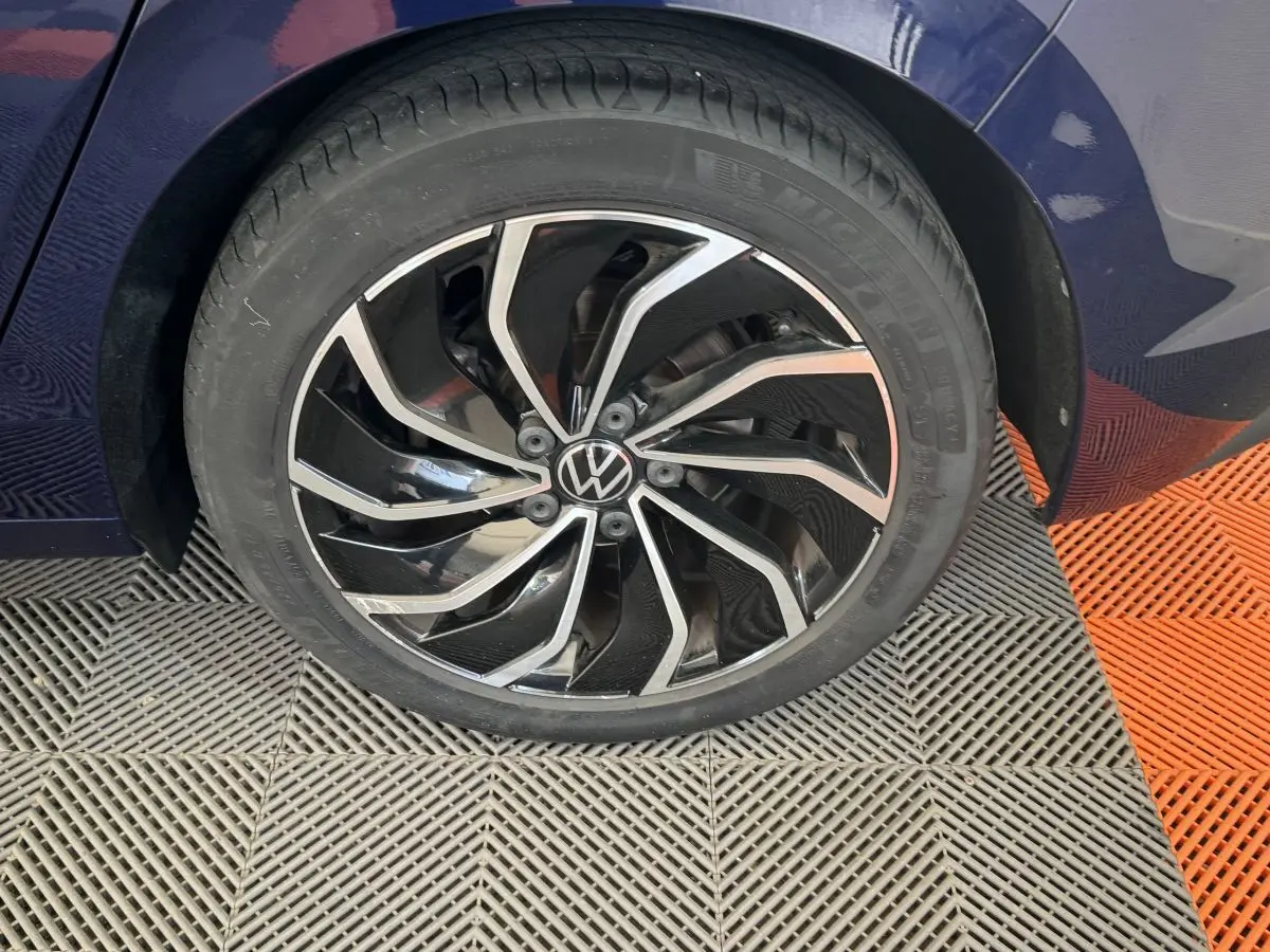 Gros plan sur la roue avant droite d'une Volkswagen Golf bleu 2021 avec jante alliage noire et argentée design moderne.