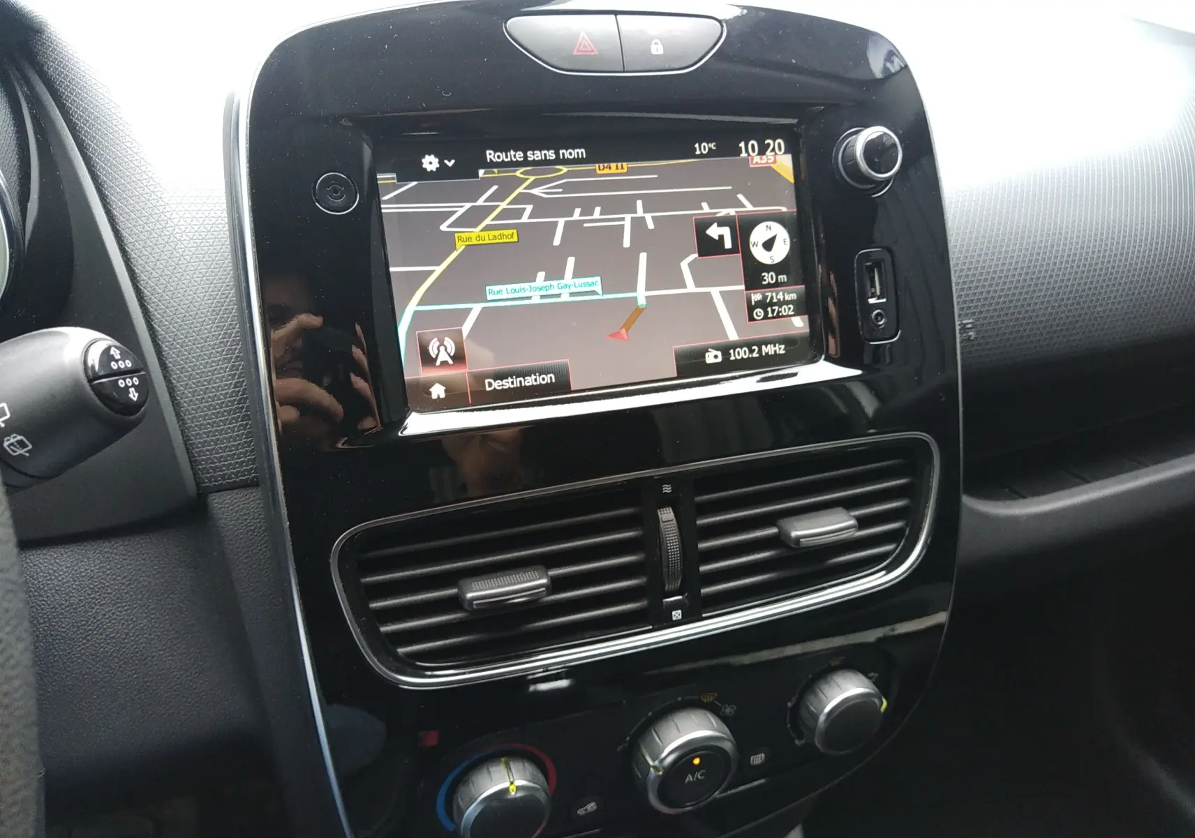 Vue rapprochée de la console centrale noire de la Renault Clio IV Société avec écran GPS et commandes de climatisation.