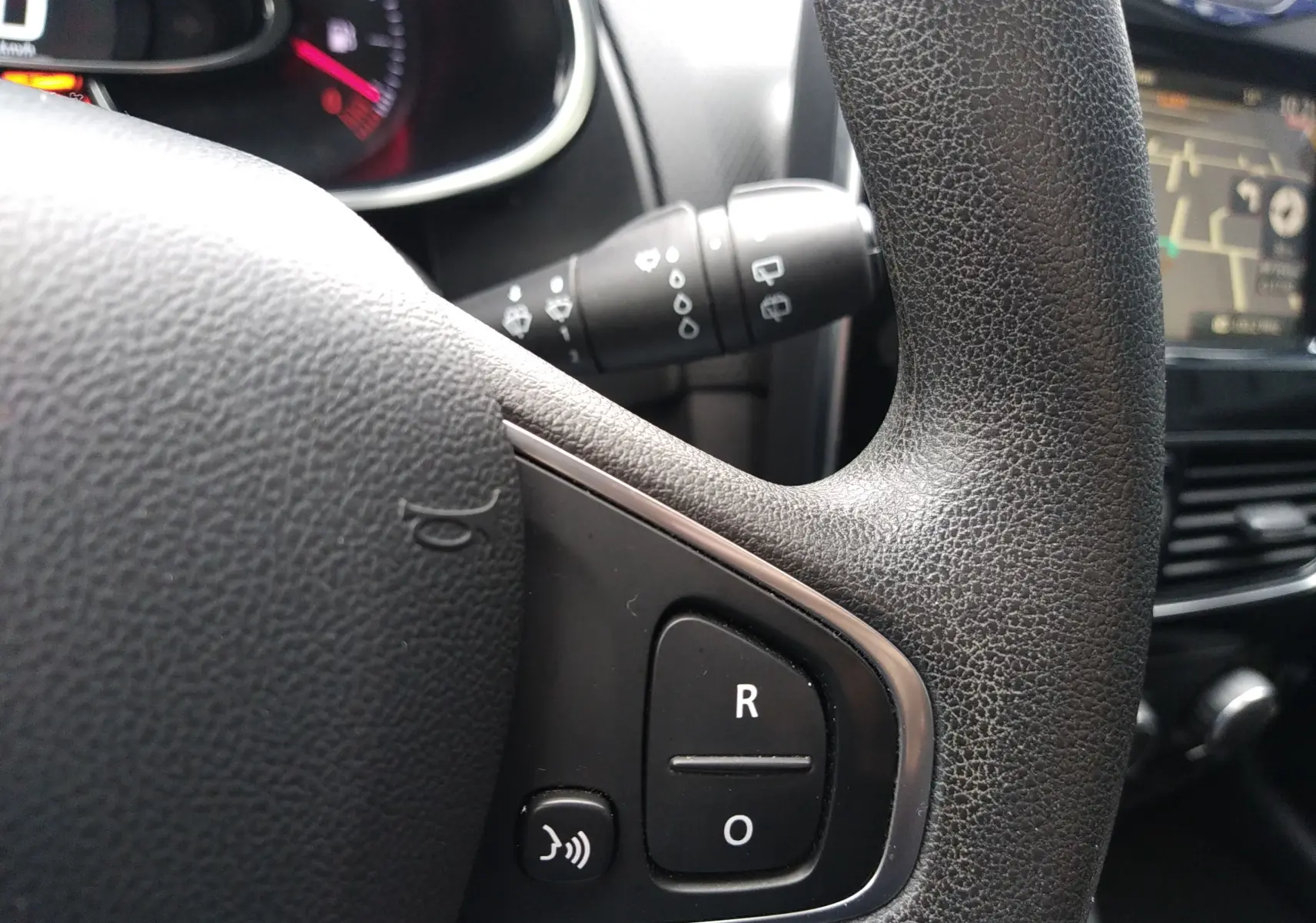 Gros plan sur le volant en cuir noir de la Renault Clio IV Société 2019 avec commandes vocales et régulateur de vitesse.