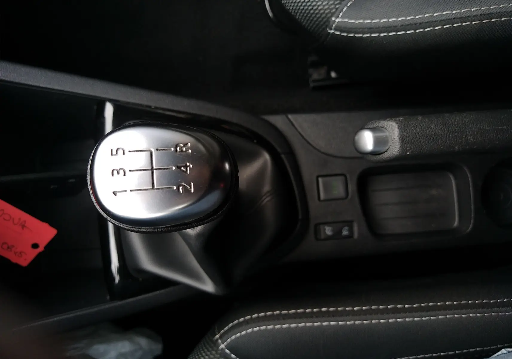 Le levier de vitesses manuel argenté de la Renault Clio IV Société blanc uni, vu de dessus, avec console et sièges en tissu noir.