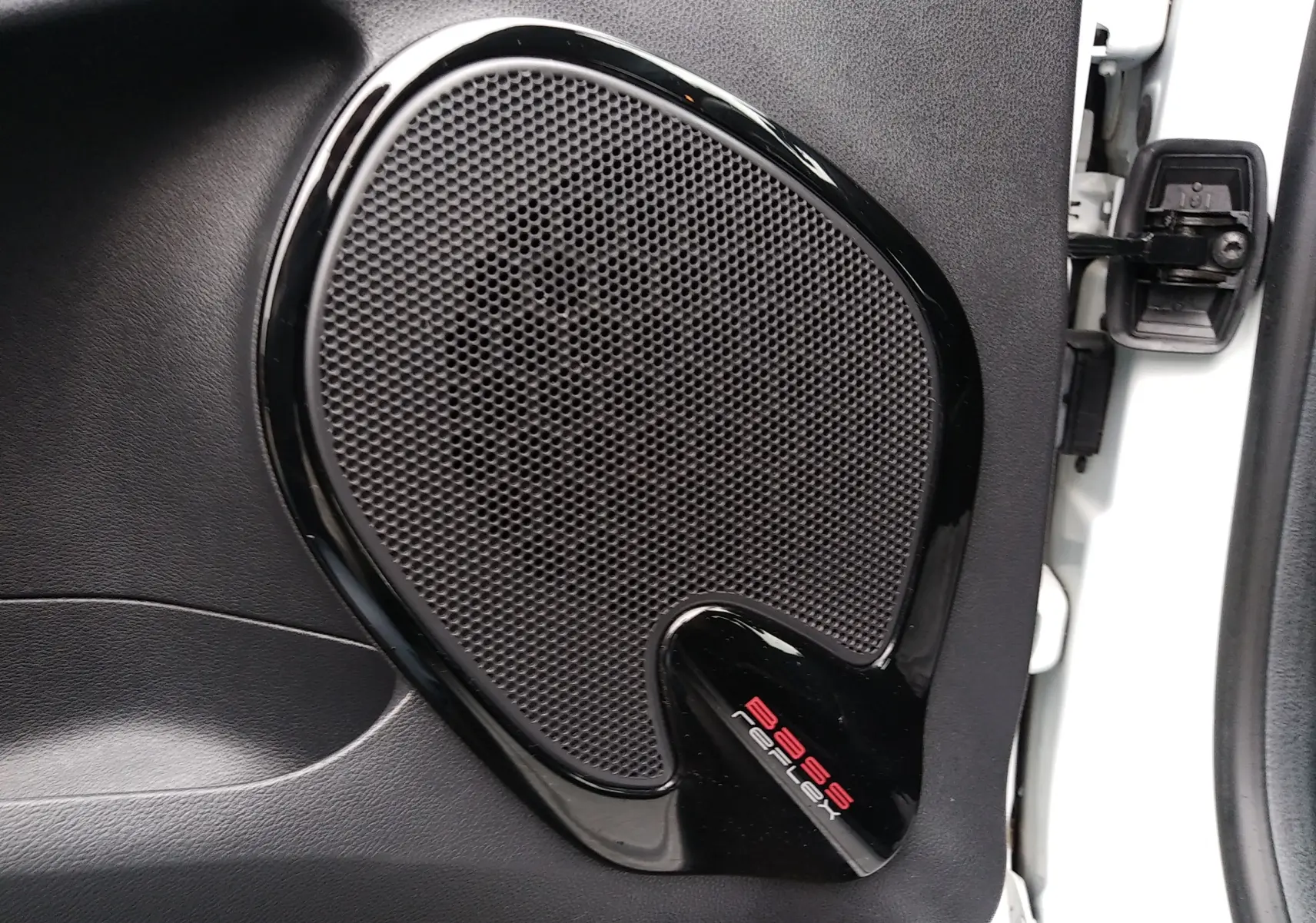 Gros plan sur l'enceinte de porte noire intégrée à la portière côté droit d'une Renault Clio IV Société blanche.