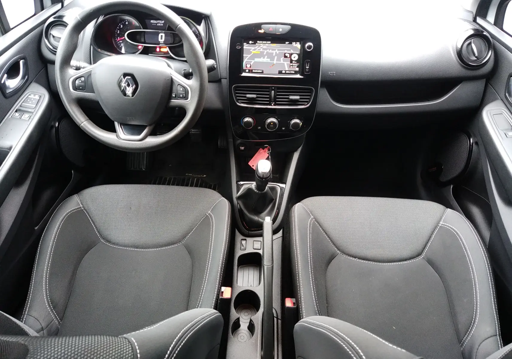 Vue intérieure avant de la Renault Clio IV Société blanche, avec tableau de bord, volant multifonction et écran GPS central.