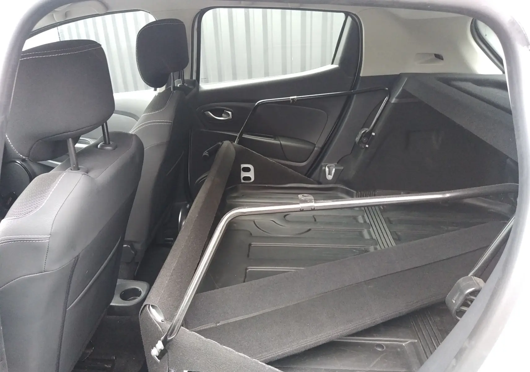 Vue intérieure arrière de la Renault Clio IV Société blanche, sièges rabattus et espace de chargement dégagé.