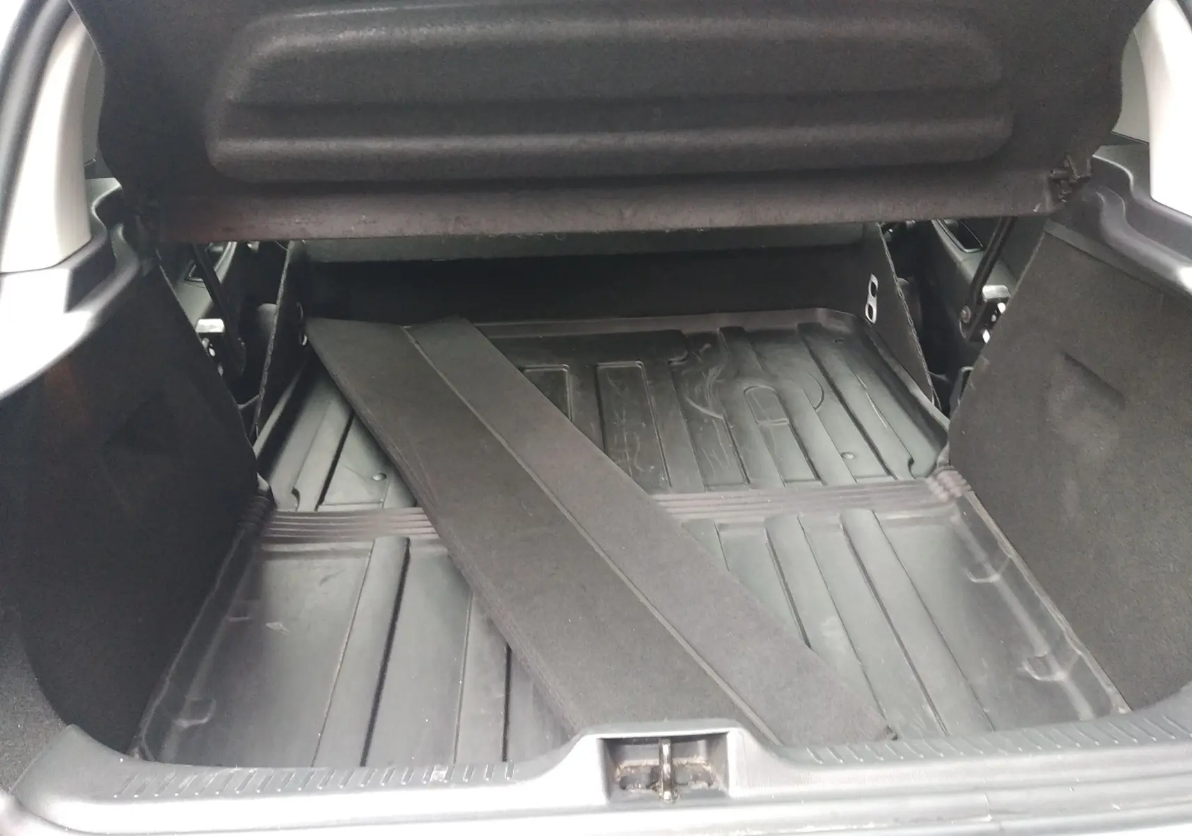 Coffre ouvert d'une Renault Clio IV Société blanche, montrant le plancher en plastique et une séparation amovible noire.