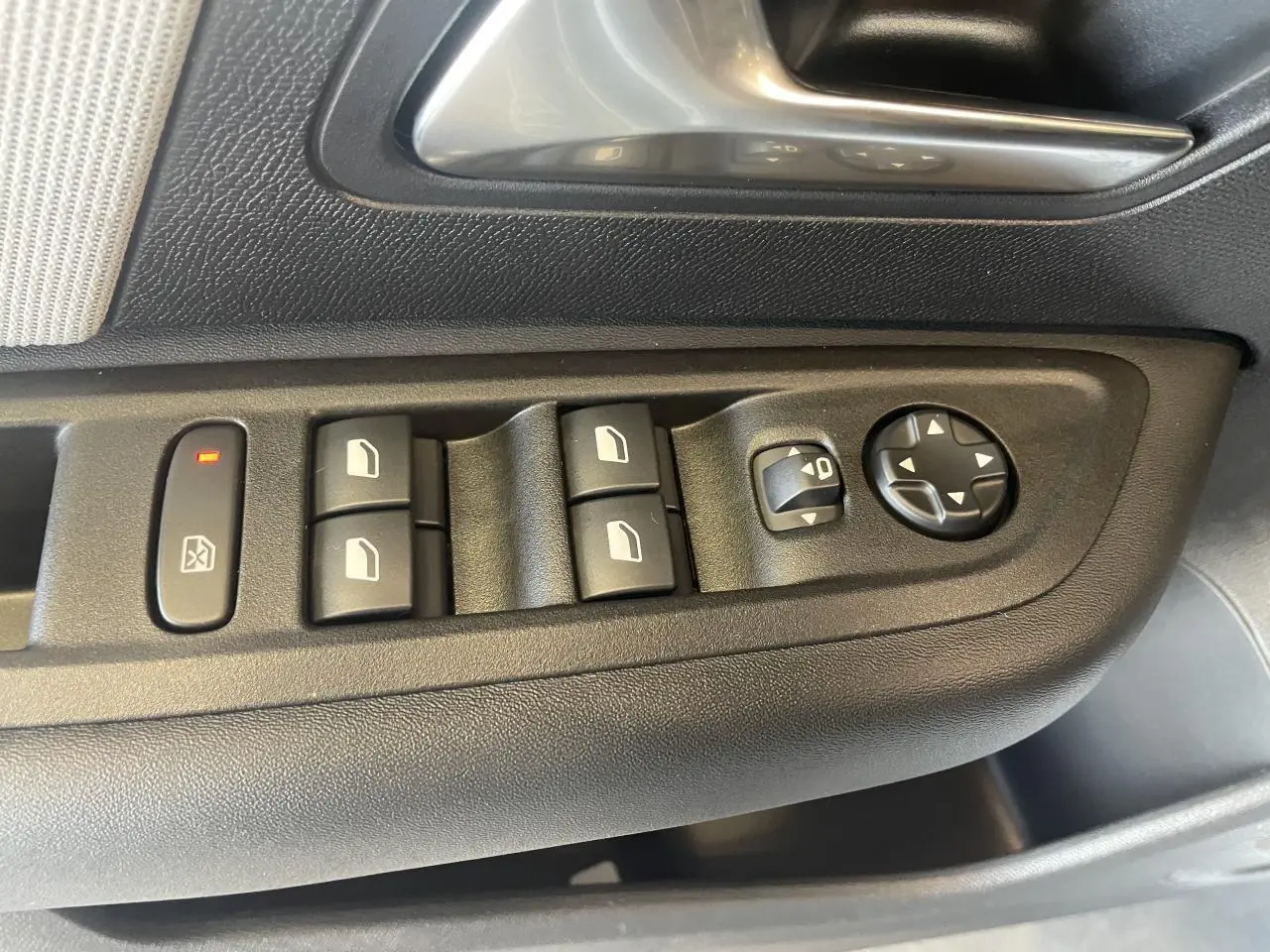 Détail des commandes de lève-vitres et réglage des rétroviseurs sur la porte côté conducteur de la Citroën C4 blanche.