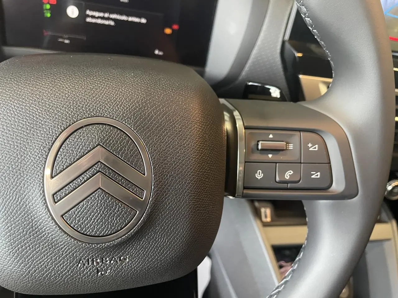 Gros plan sur le volant cuir noir de la Citroën C4 2025 avec commandes intégrées et logo chromé central.