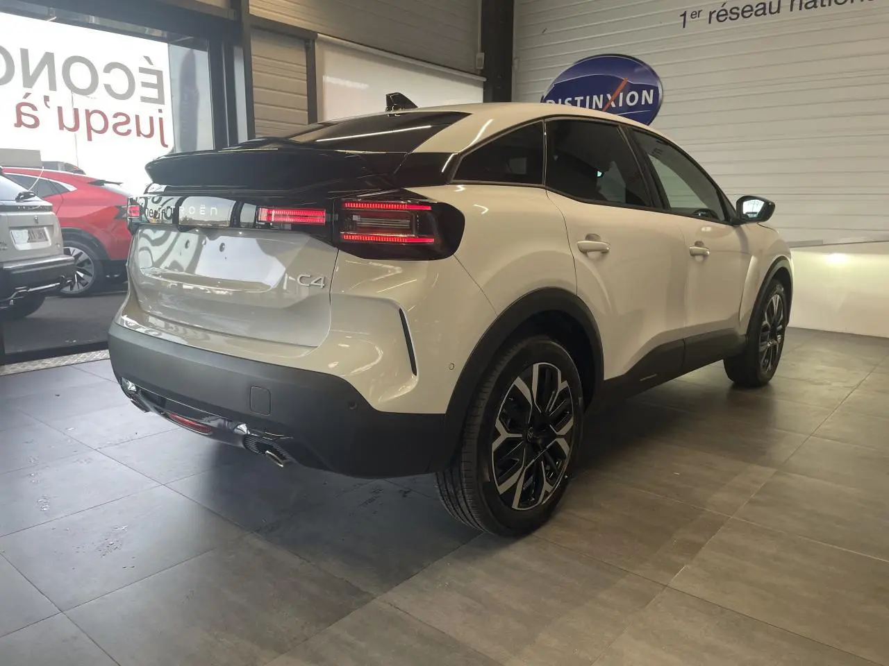 Vue 3/4 arrière droite d'une Citroën C4 blanche métallisée avec toit noir et jantes alliage 18 pouces.