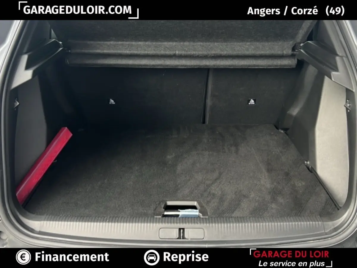 Coffre ouvert d’un Peugeot 2008 Hybrid gris clair, vue arrière montrant l’espace de chargement et un triangle de signalisation rouge sur le côté gauche.