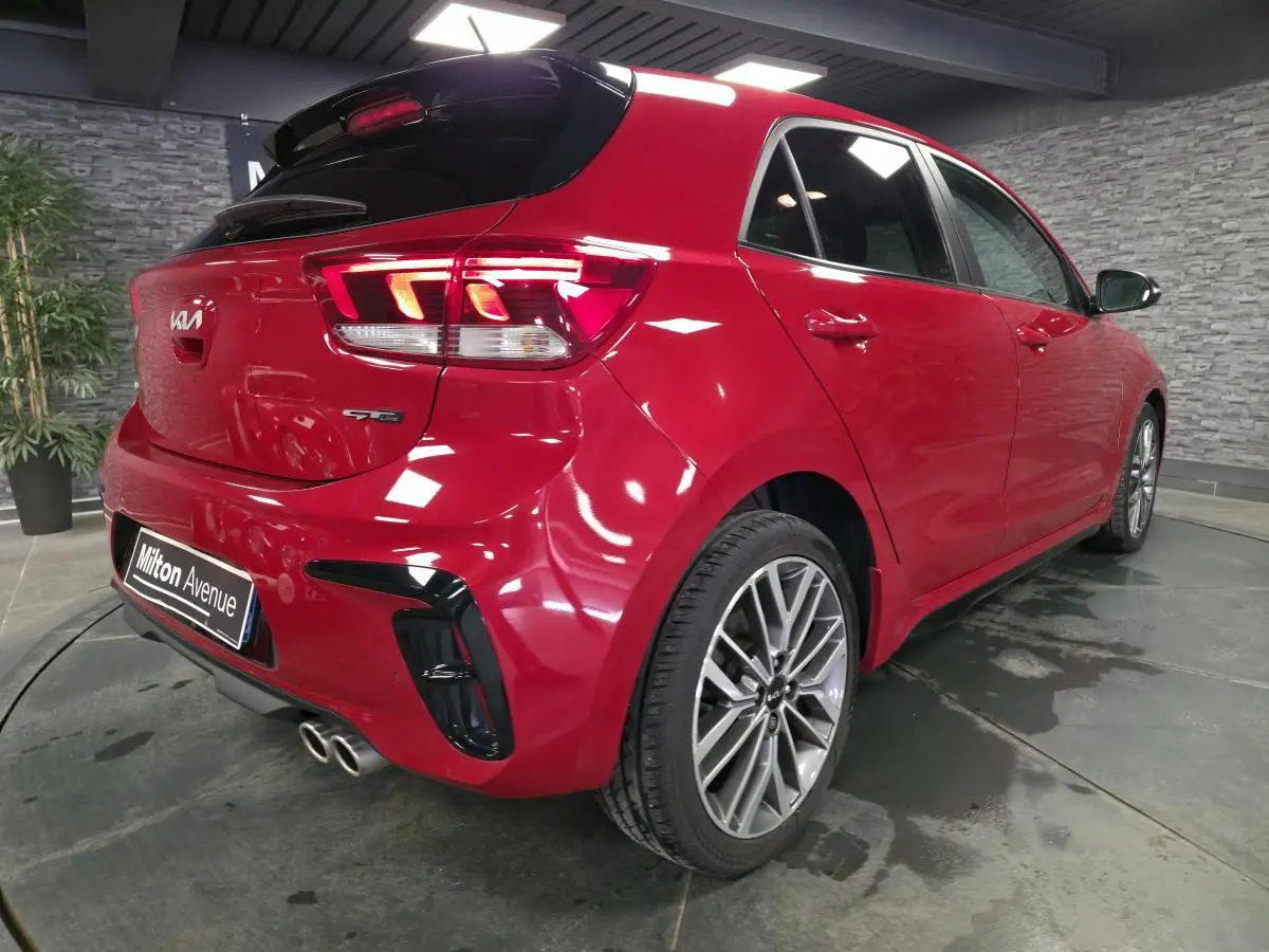 Vue 3/4 arrière droite de la KIA Rio GT Line rouge métallisée avec double sortie d'échappement chromée et jantes alliage 17 pouces.