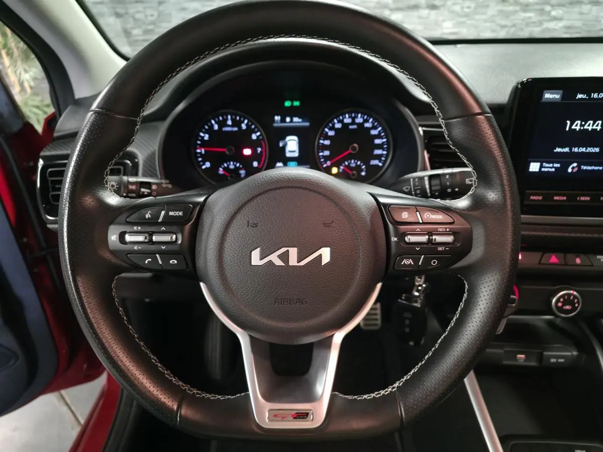 Vue rapprochée du volant cuir perforé noir de la KIA Rio GT Line 2022 avec commandes intégrées et tableau de bord digital.