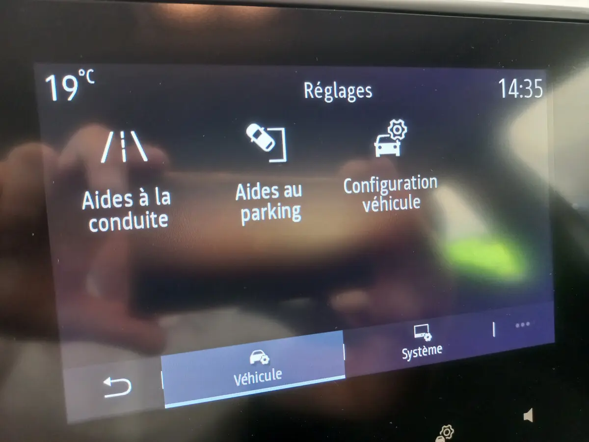 Écran tactile central de la Renault Clio Business blanc 2021 affichant les réglages d'aides à la conduite et parking.