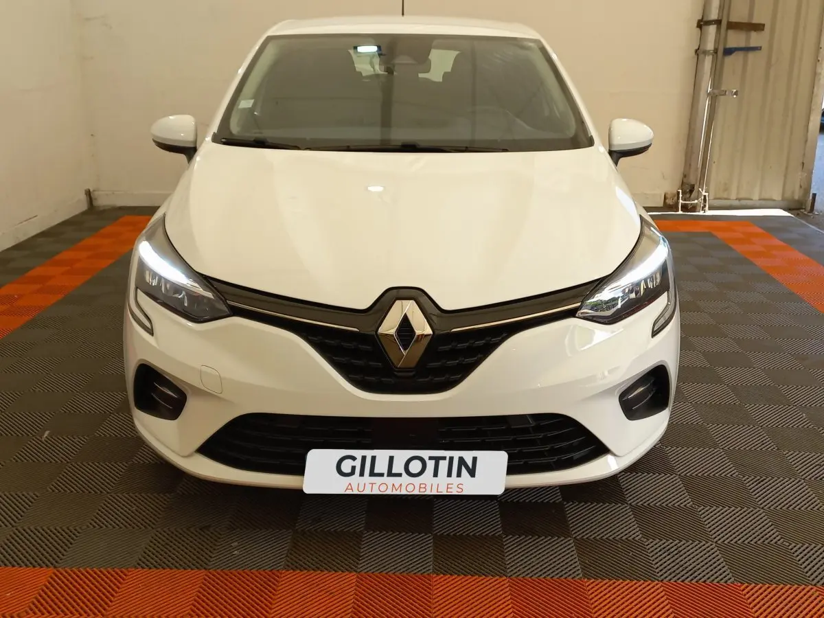 Vue frontale d'une Renault Clio Business SCe 65 blanche avec phares LED allumés dans un garage.