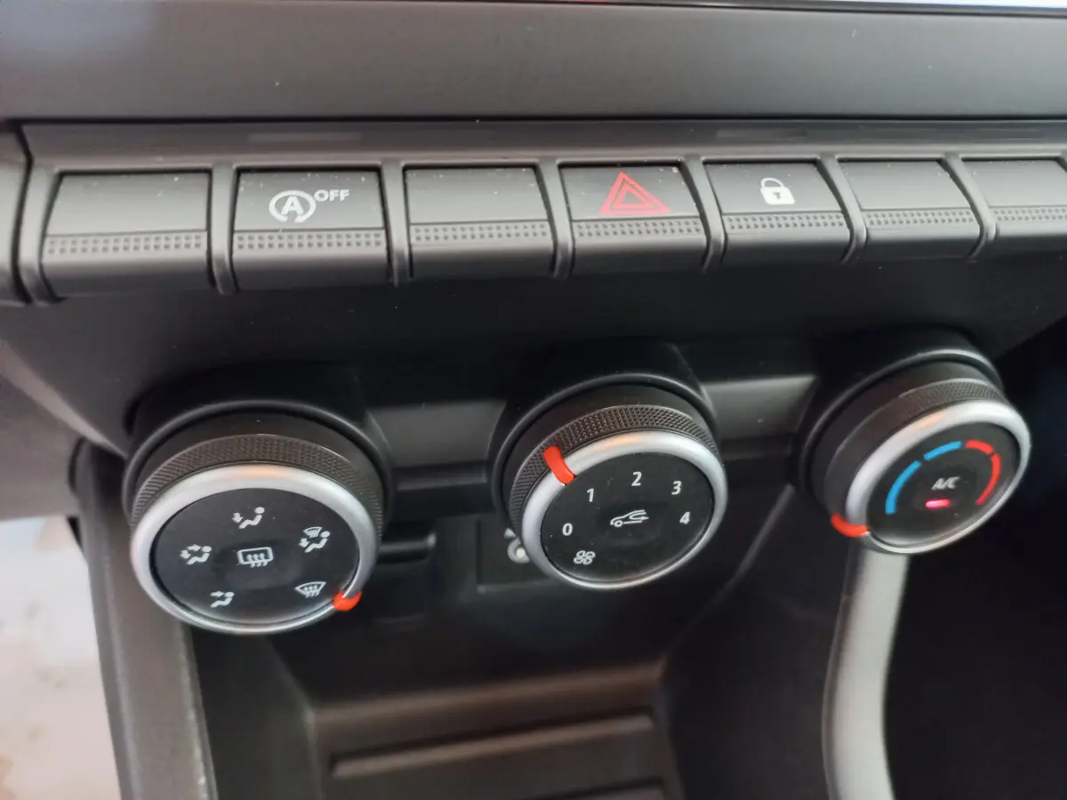 Gros plan sur les commandes de climatisation et boutons de fonction du tableau de bord noir de la Renault Clio Business blanche 2021.