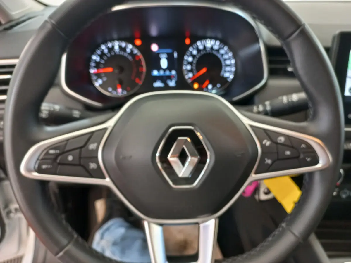 Vue rapprochée du volant cuir noir multifonctions de la Renault Clio Business blanche, avec commandes intégrées.