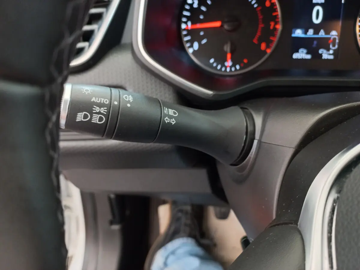 Gros plan sur la commande des feux et le tableau de bord numérique de la Renault Clio Business blanche de 2021.