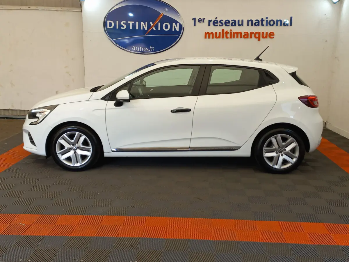 Profil côté droit d'une Renault Clio Business blanche de 2021, avec jantes alliage et vitres teintées, en intérieur showroom.