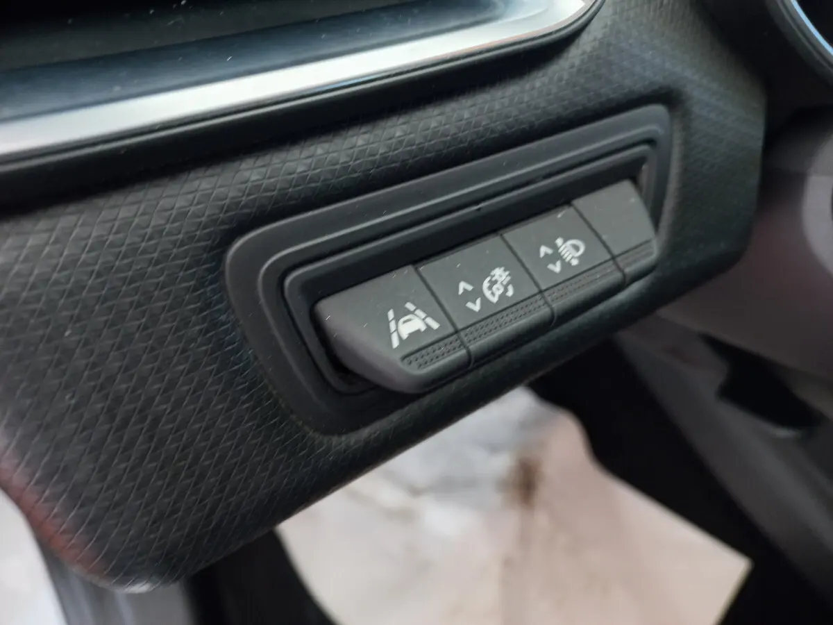 Gros plan sur les boutons de réglage d'assistance à la conduite dans l'habitacle noir d'une Renault Clio Business blanche.