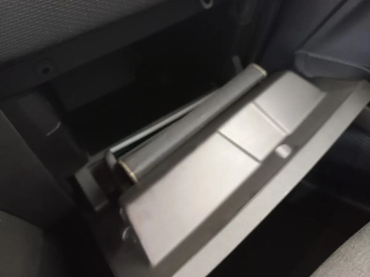 Gros plan sur le rangement ouvert côté passager de la Renault Clio Business blanche, intérieur sombre visible.