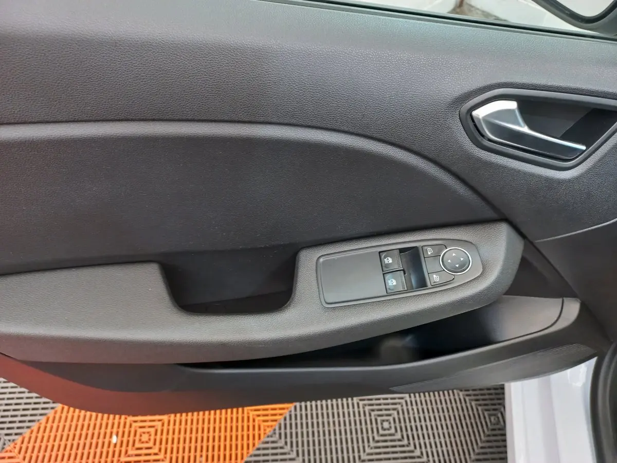 Gros plan sur la porte côté conducteur noire de la Renault Clio Business blanche, avec commandes électriques des vitres et rétroviseurs.