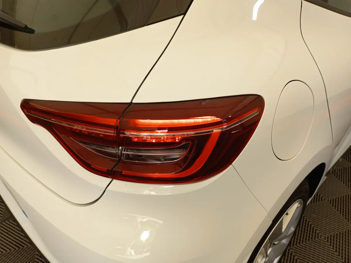 Gros plan sur le feu arrière droit d'une Renault Clio Business blanche, mettant en valeur la carrosserie lisse et la trappe à carburant.