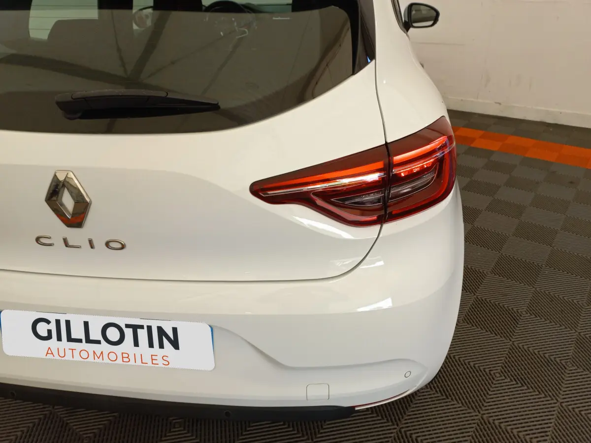 Vue arrière droite d'une Renault Clio Business blanche avec feux arrière LED et logo distinctif sur coffre.