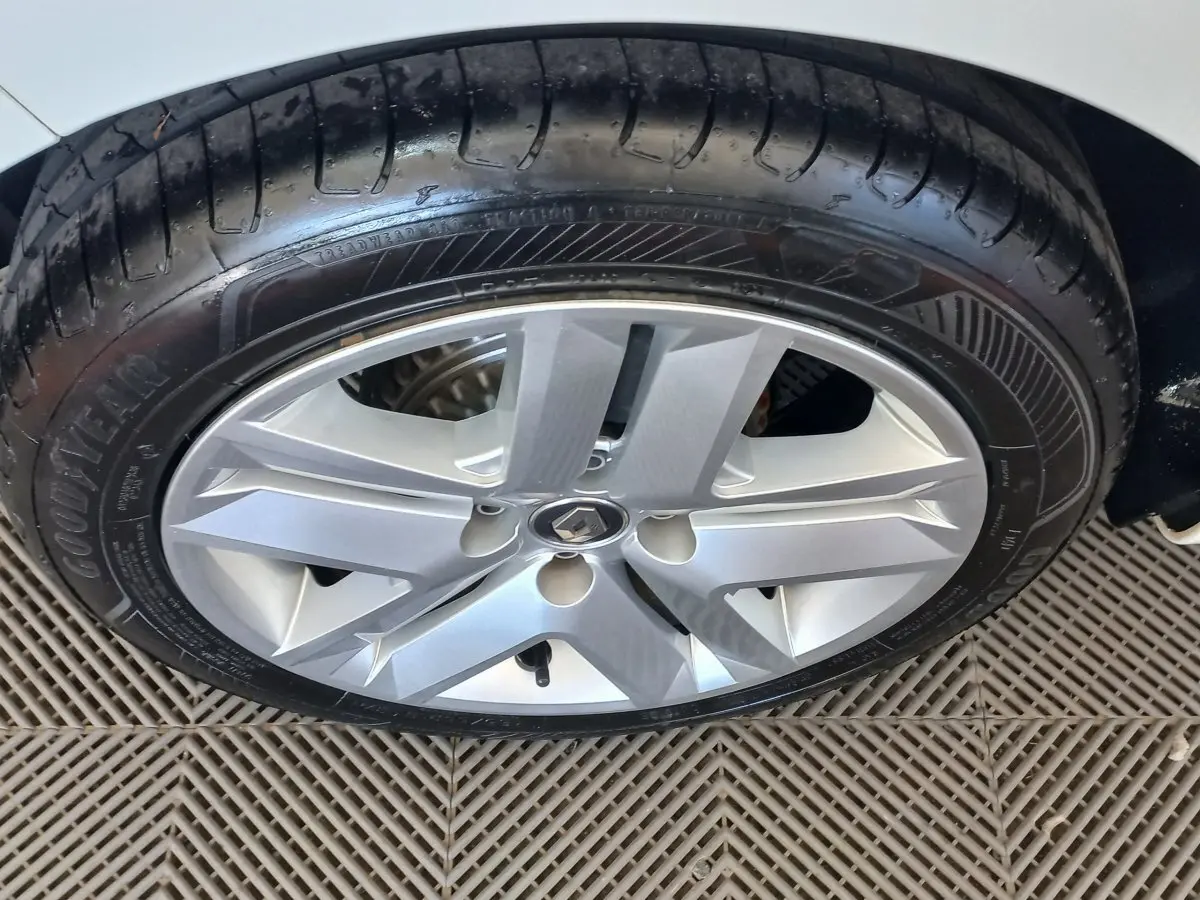 Gros plan sur la roue avant droite d'une Renault Clio blanche, mettant en valeur la jante alliage et le pneu Goodyear.