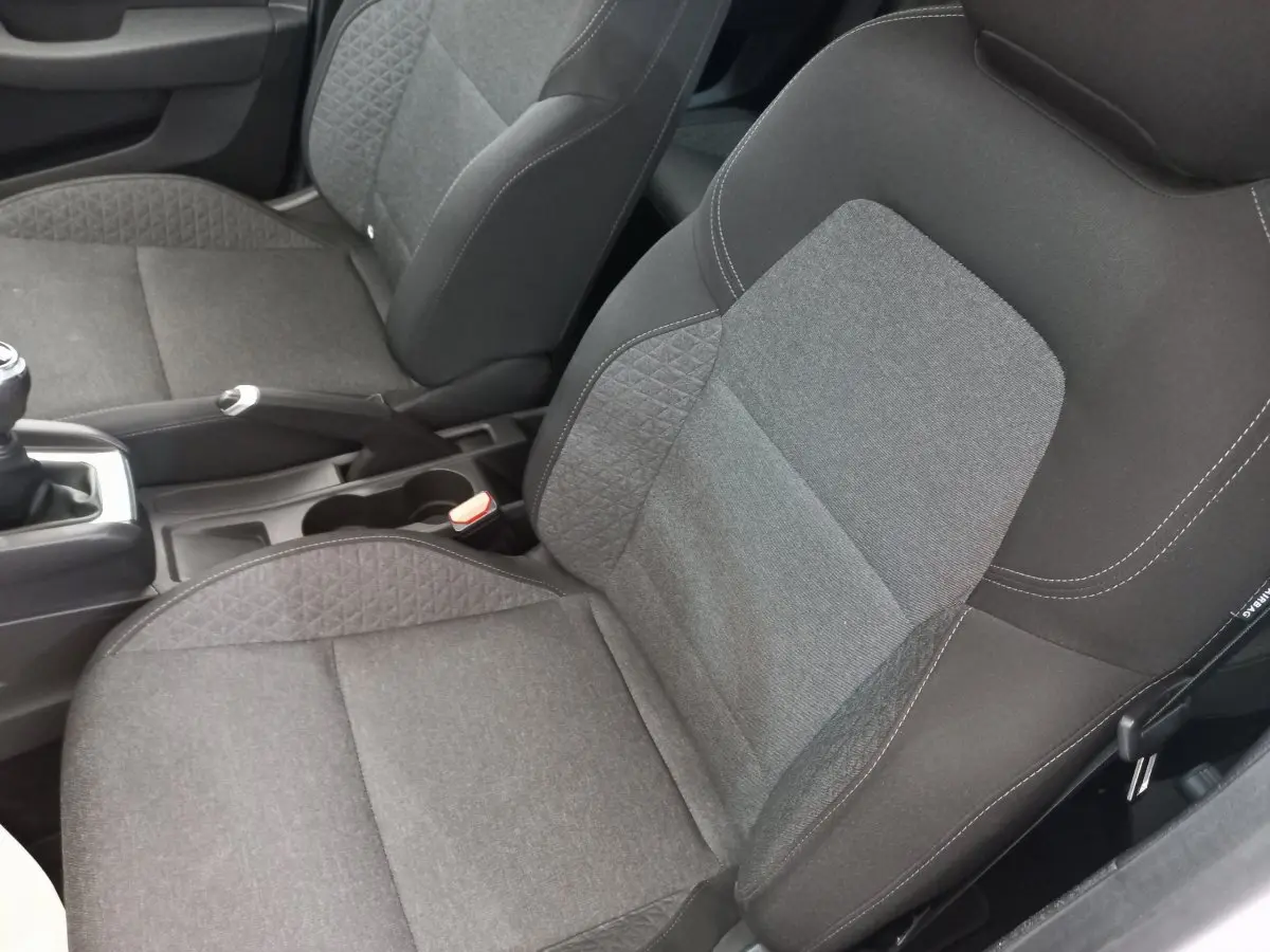 Vue rapprochée des sièges avant gris foncé de la Renault Clio Business SCe 65 blanche, avec levier de vitesse manuel visible.