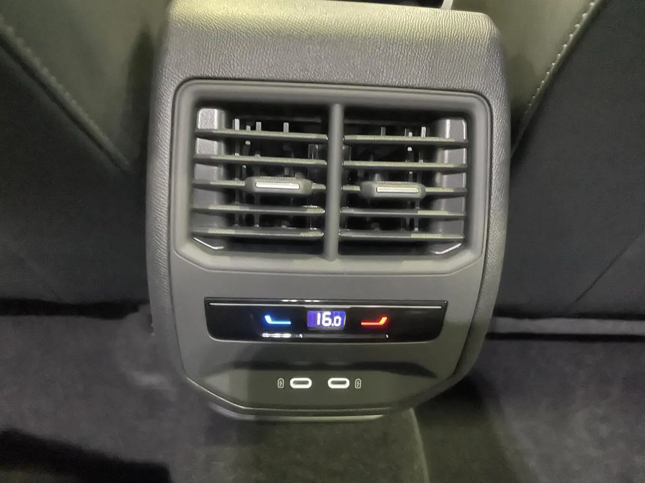 Gros plan sur la console arrière noire avec bouches d’aération, réglage climatisation à 16°C et deux ports USB-C.